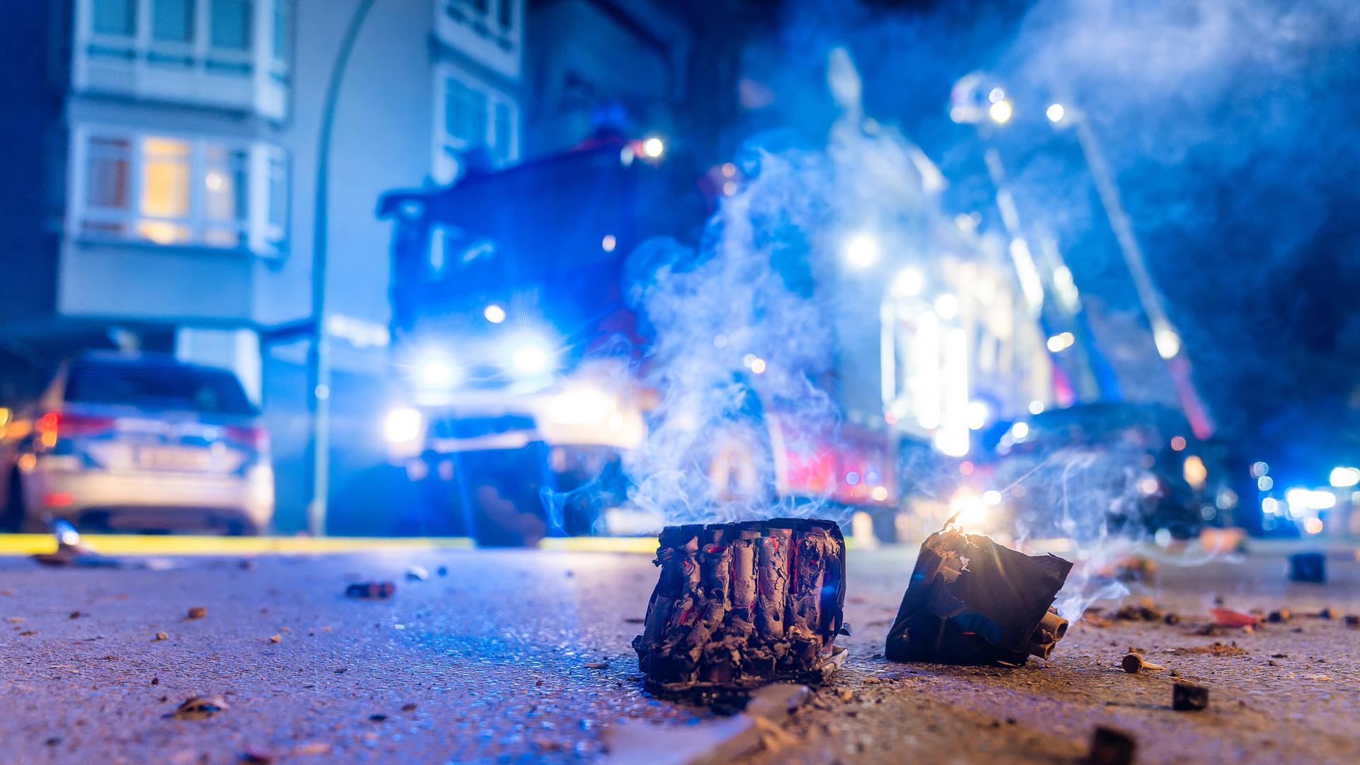 Auf einer nächtlichen Straße liegt abgebranntes Feuerwerk, dahinter steht ein Feuerwehrauto. Auf einer nächtlichen Straße liegt abgebranntes Feuerwerk, dahinter steht ein Feuerwehrauto.