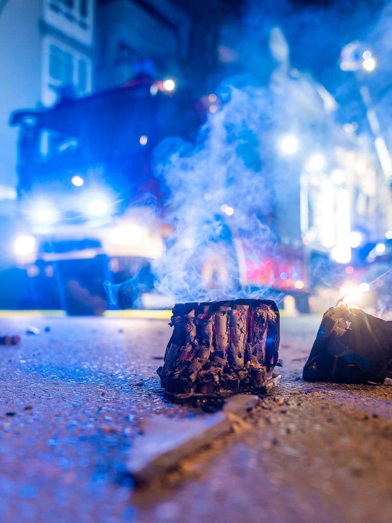 Auf einer nächtlichen Straße liegt abgebranntes Feuerwerk, dahinter steht ein Feuerwehrauto.