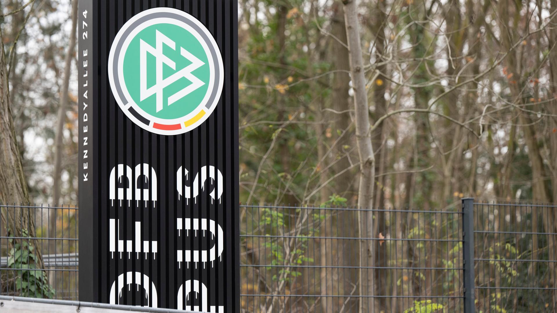 Hinter einem Bauzaun steht das DFB-Logo an einer Zufahrt zum DFB-Campus in Frankfurt.
