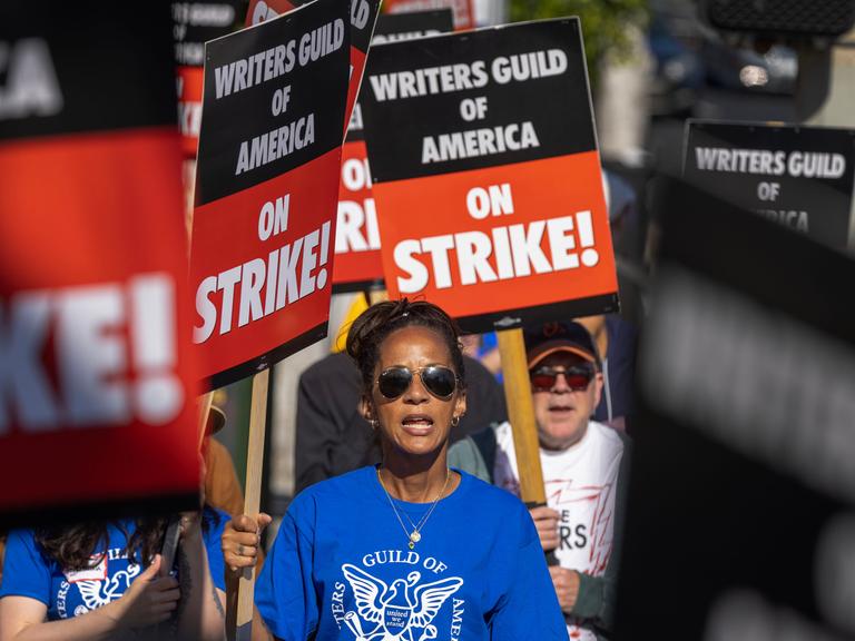 Mehrere Personen tragen Schilder mit der Aufschrift "Writers Guild of America on Strike"