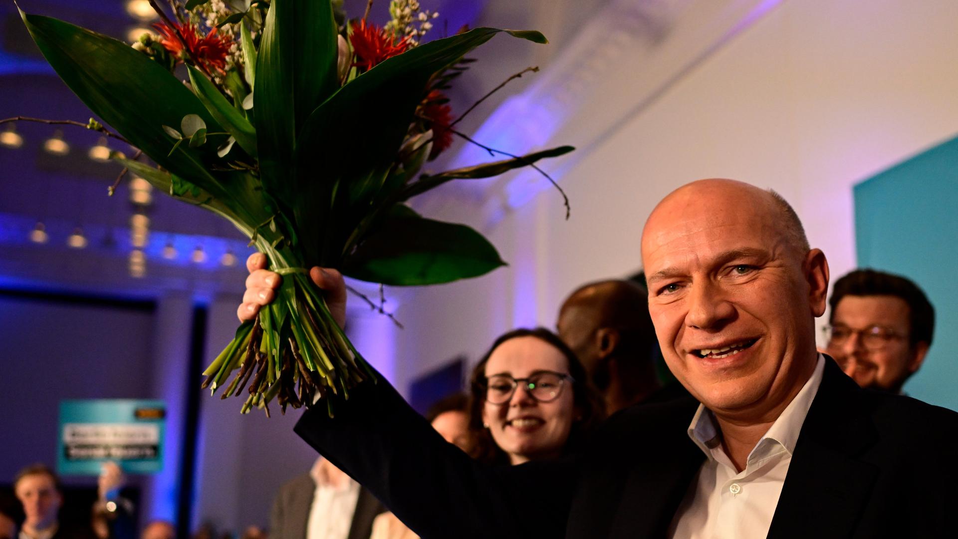 CDU-Spitzenkandidat Kai Wegner mit einem Blumenstrauß auf der Bühne der CDU-Wahlparty.