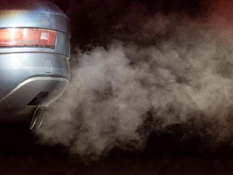 Abgase kommen aus dem Auspuff eines Autos und werden in der kalten Morgenluft sichtbar.