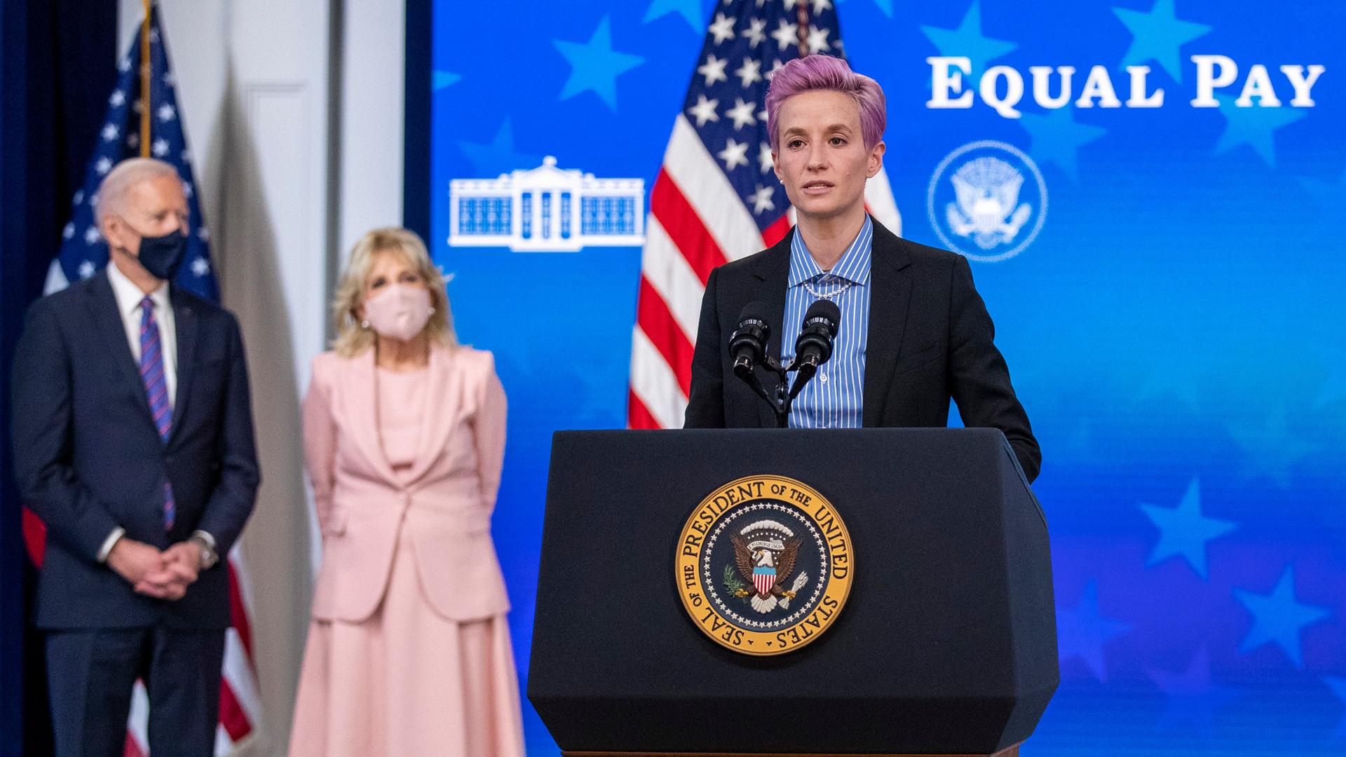 US-Fußballerin Megan Rapinoe am Rednerpult vor US-Präsident Joe Biden und First Lady Jill Biden, im Hintergrund steht "Equal pay day" US-Fußballerin Megan Rapinoe am Rednerpult vor US-Präsident Joe Biden und First Lady Jill Biden, im Hintergrund steht "Equal pay day"