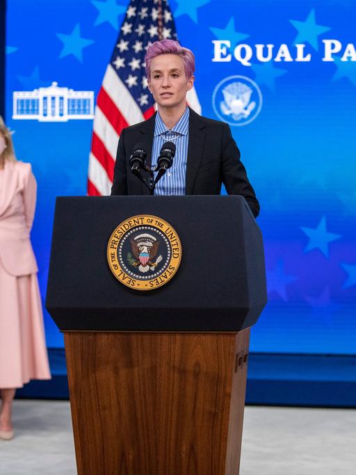 US-Fußballerin Megan Rapinoe am Rednerpult vor US-Präsident Joe Biden und First Lady Jill Biden, im Hintergrund steht "Equal pay day"
