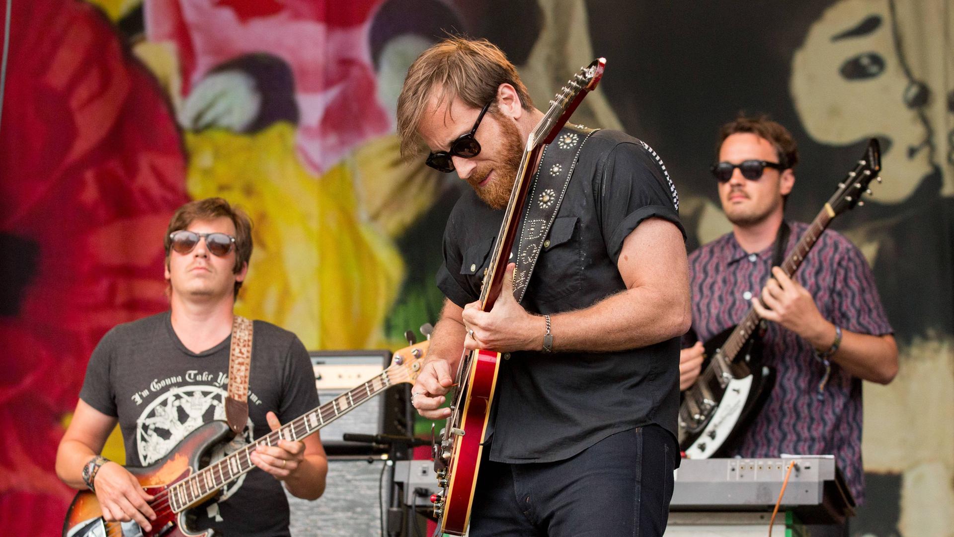 Der Gitarrist Dan Auerbach steht mit Gitarre und seiner Band  "The Arcs" auf einer Bühne