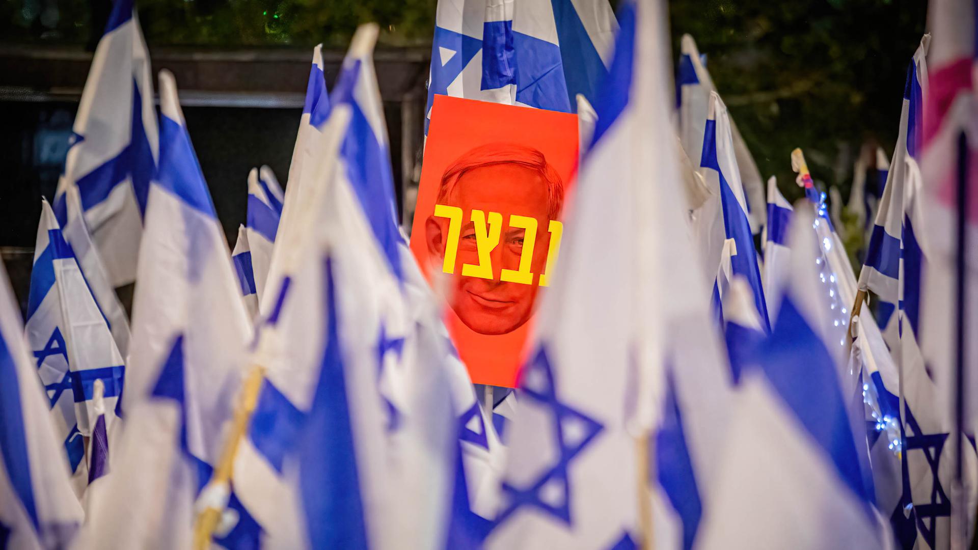 Hunderttausende Menschen demonstrieren im April gegen Netanjahus Pläne zur Reform des Justizwesens. Zwischen blau-weißen Israel-Flaggen ist ein Plakat mit dem Konterfei Netanjahus zu sehen auf dem auf Hebräisch "Unfähigkeit" steht. 