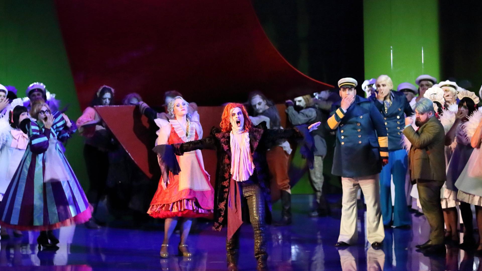 Die Solisten und der Chor der "Holländer"-Inszenierung stehen in bunten Kostümen auf der Bühne der Komischen Oper Die Solisten und der Chor der "Holländer"-Inszenierung stehen in bunten Kostümen auf der Bühne der Komischen Oper