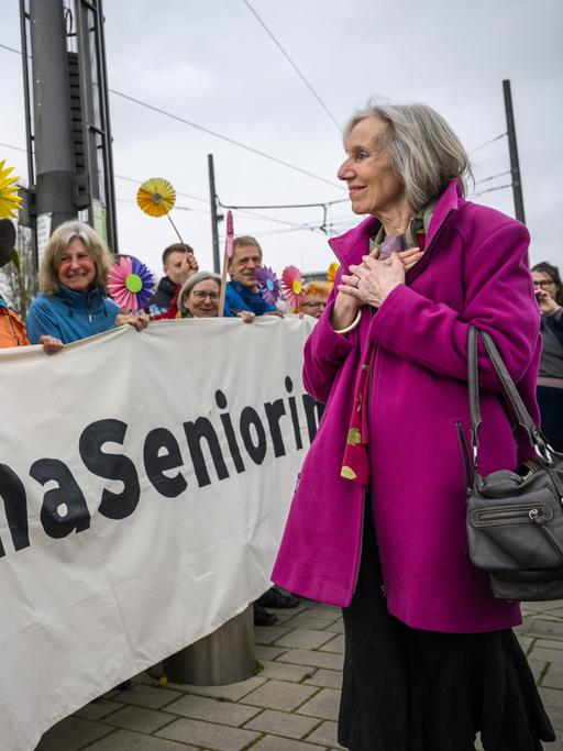Die Klimaaktivistin Rosmarie Wydler-Wält blickt auf ihre Mitstreiterinnen, die ein Banner tragen mit der AUfschrift "KlimaSeniorinnen". 