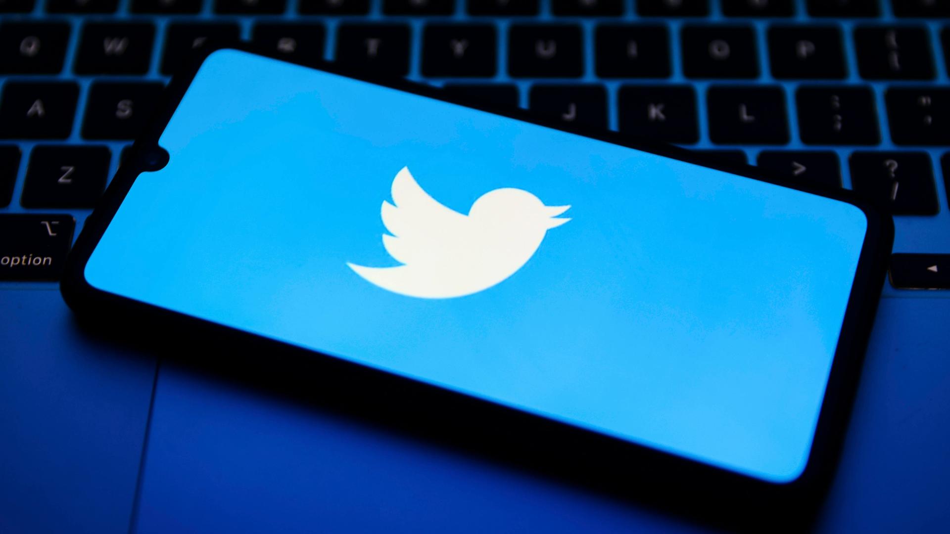 Das Twitter-Logo auf einem Smartphone, das auf einem Laptop liegt. Das Twitter-Logo auf einem Smartphone, das auf einem Laptop liegt.