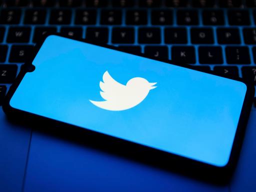 Das Twitter-Logo auf einem Smartphone, das auf einem Laptop liegt.
