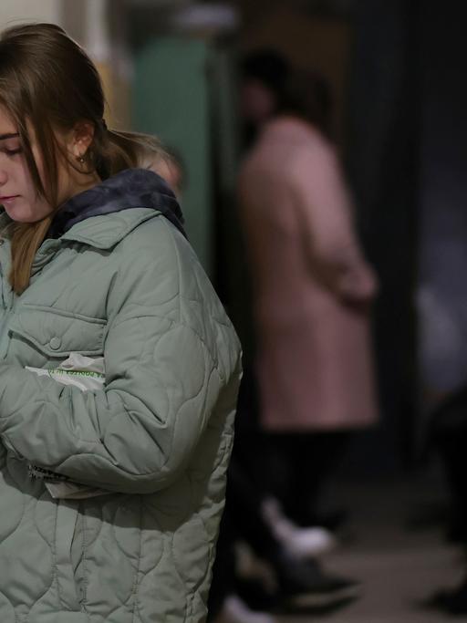 Eine junge Frau steht in einem Schutzbunker in Liviv, Ukraine. und schaut auf ihr Smartphone.