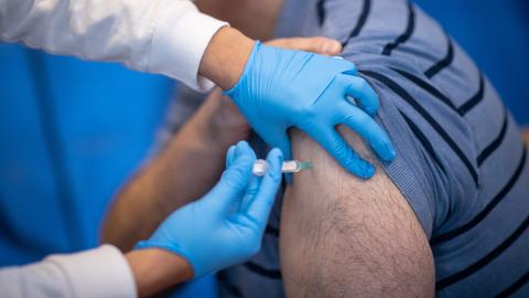 Eine Mitarbeiterin eines Impfzentrums verabreicht einem Mann eine Impfung mit dem Corona-Impfstoff.