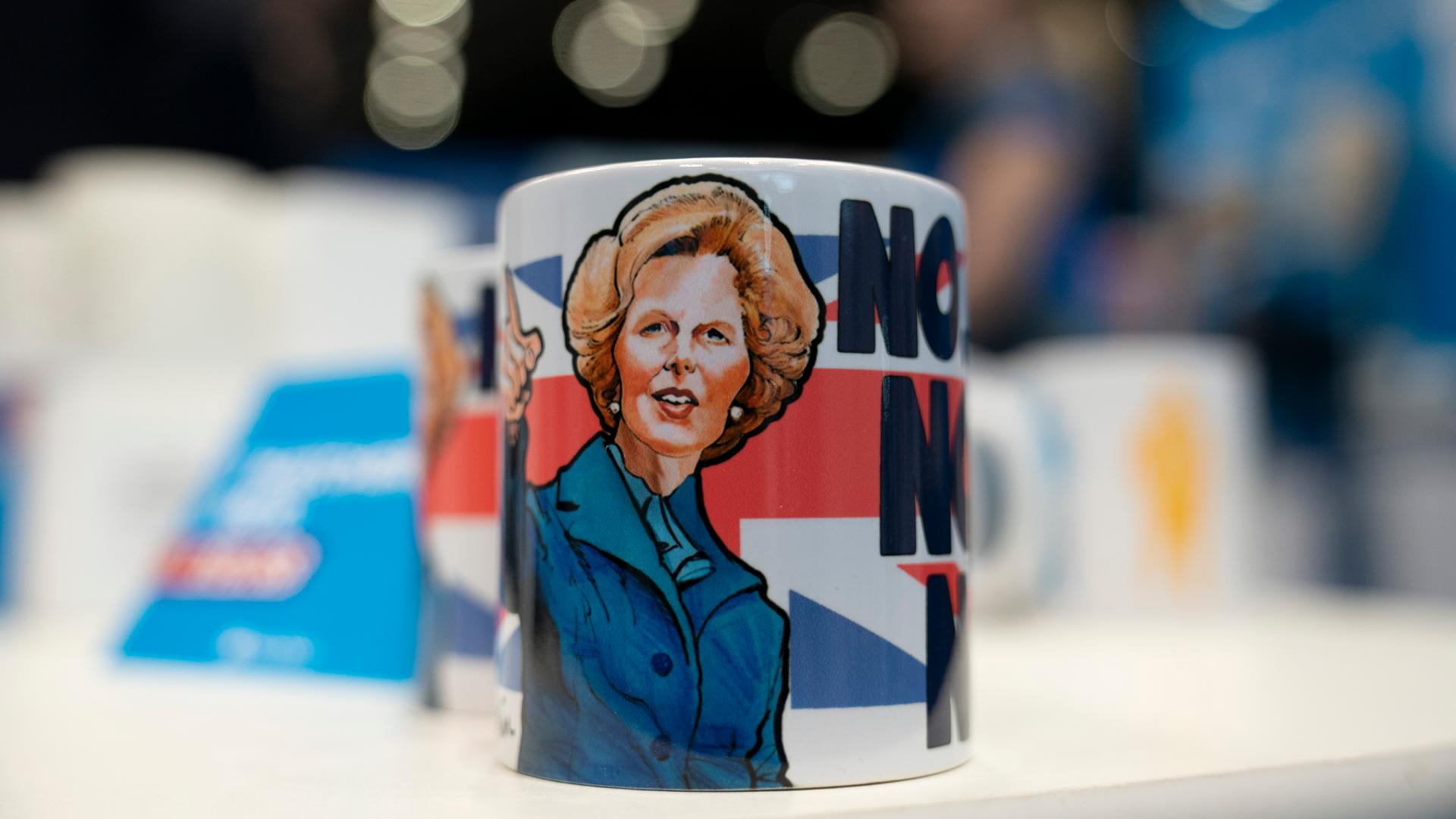 Eine Tasse mit dem der Illustration der ehemaligen britischen Premierministerin Margaret Thatcher - im Hintergrund ist die britische Flagge zu sehen.