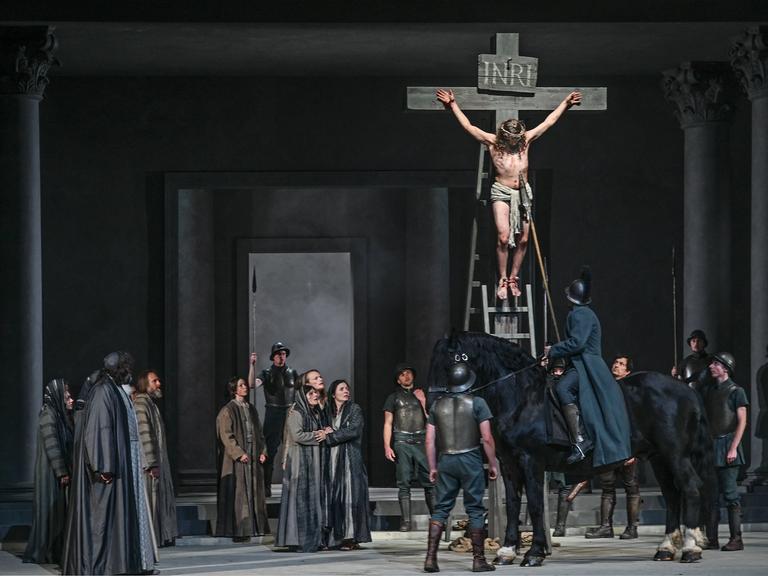 Bei der Fotoprobe zu den 42. Oberammergauer Passionsspiele sind rund zwei Dutzend Menschen auf der Bühne. Jesus hängt am Kreuz, ein römischer Soldat sticht mit einer Lanze in Jesu Brust.