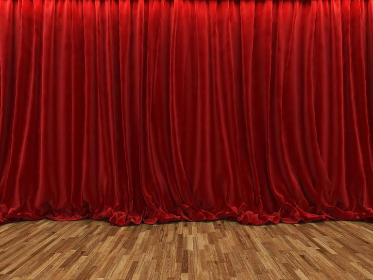Ein geschlossener roter Samtvorhang in einem Theater.