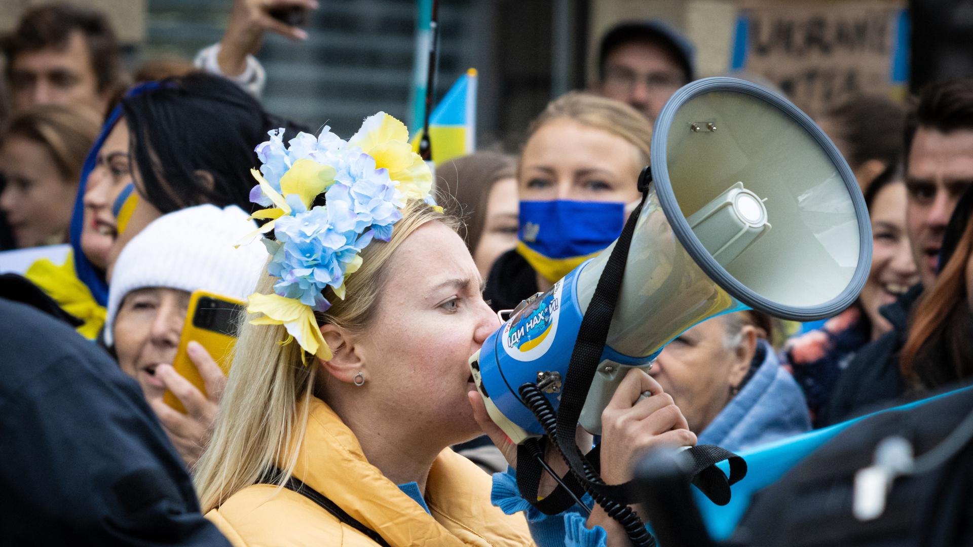 Auf einer Solidaritätsdemonstration für die Ukraine spricht eine Frau in ein Megafon. 
