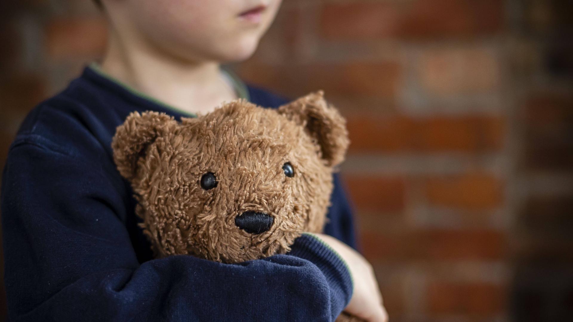 Ein hellbrauner Teddy im Arm eines kleinen Jungen Ein hellbrauner Teddy im Arm eines kleinen Jungen