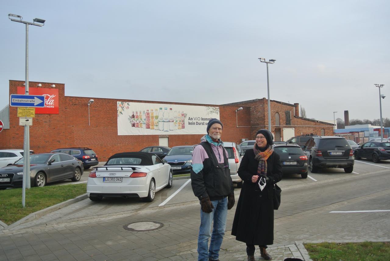 Auf einem Parkplatz vor dem Coca-Cola-Werk in Lüneburg stehen ein Mann und eine Frau.