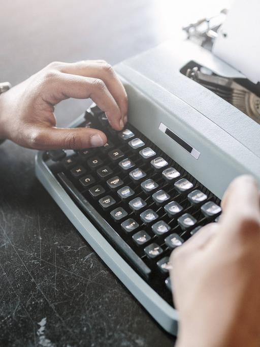 Eine Person schreibt an einer Schreibmaschine. 