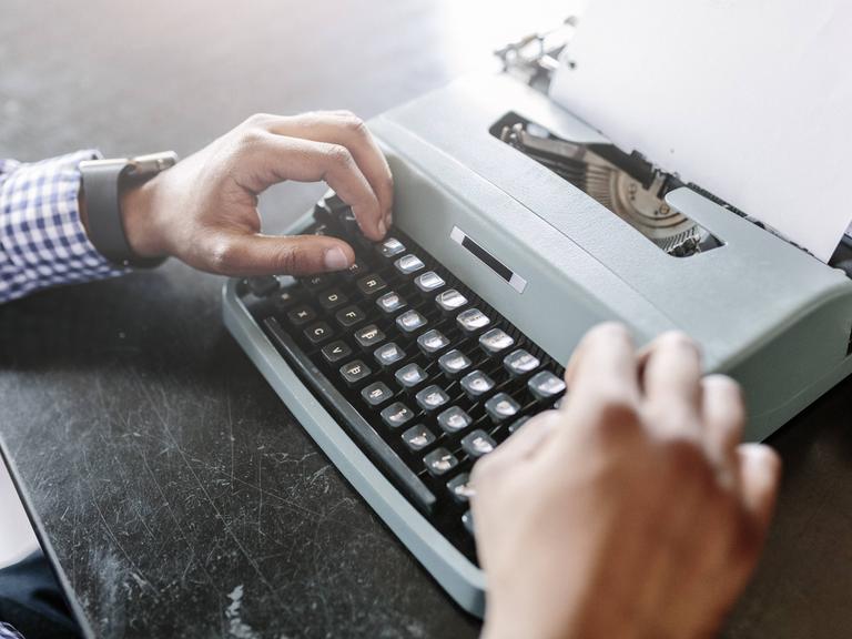 Eine Person schreibt an einer Schreibmaschine. 