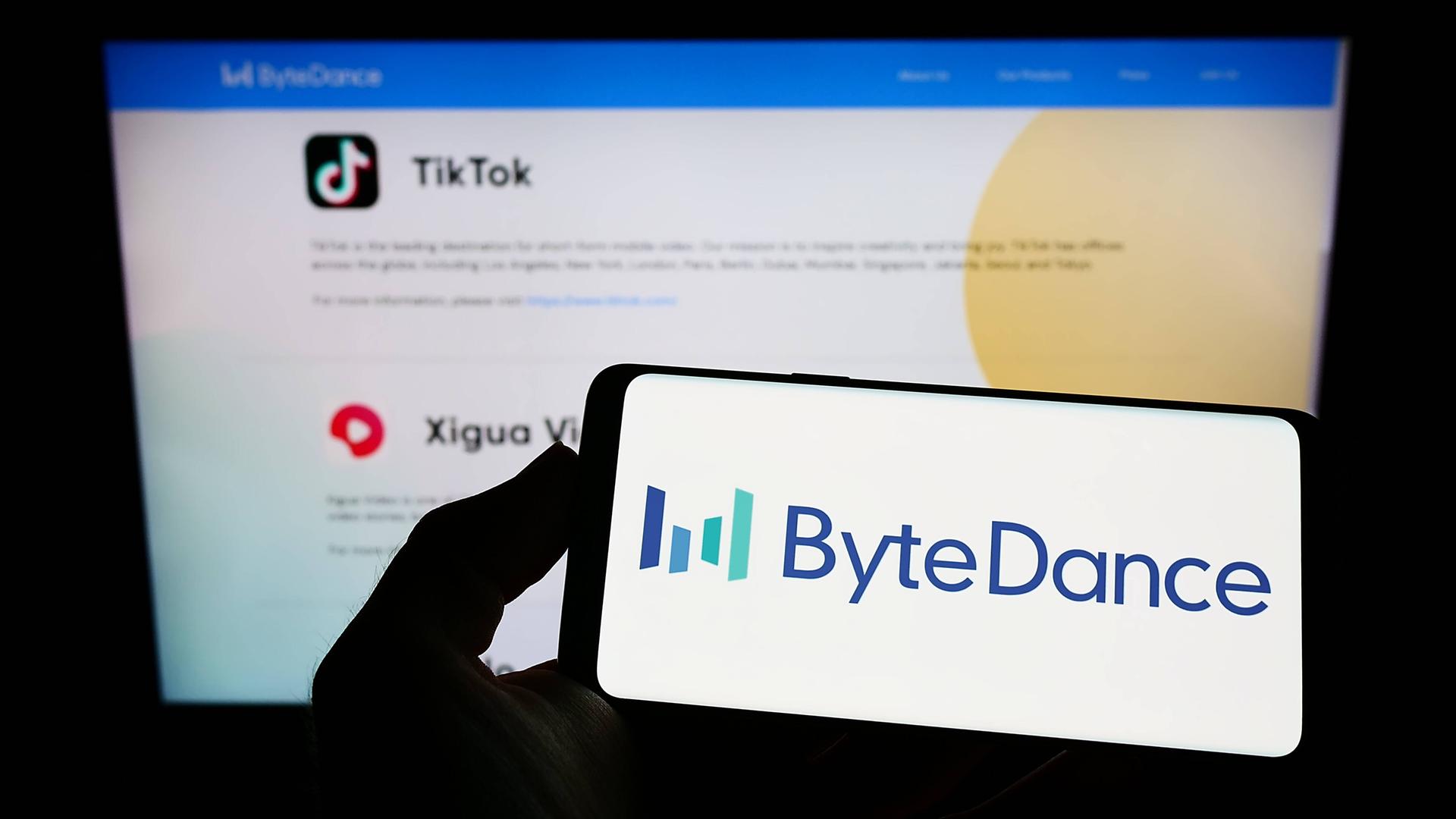 Auf einem Handydisplay ist der Schriftzug Bytedance zu sehen und dahinter ein TikTok-Logo auf einem Computerbildschrim. Auf einem Handydisplay ist der Schriftzug Bytedance zu sehen und dahinter ein TikTok-Logo auf einem Computerbildschrim.