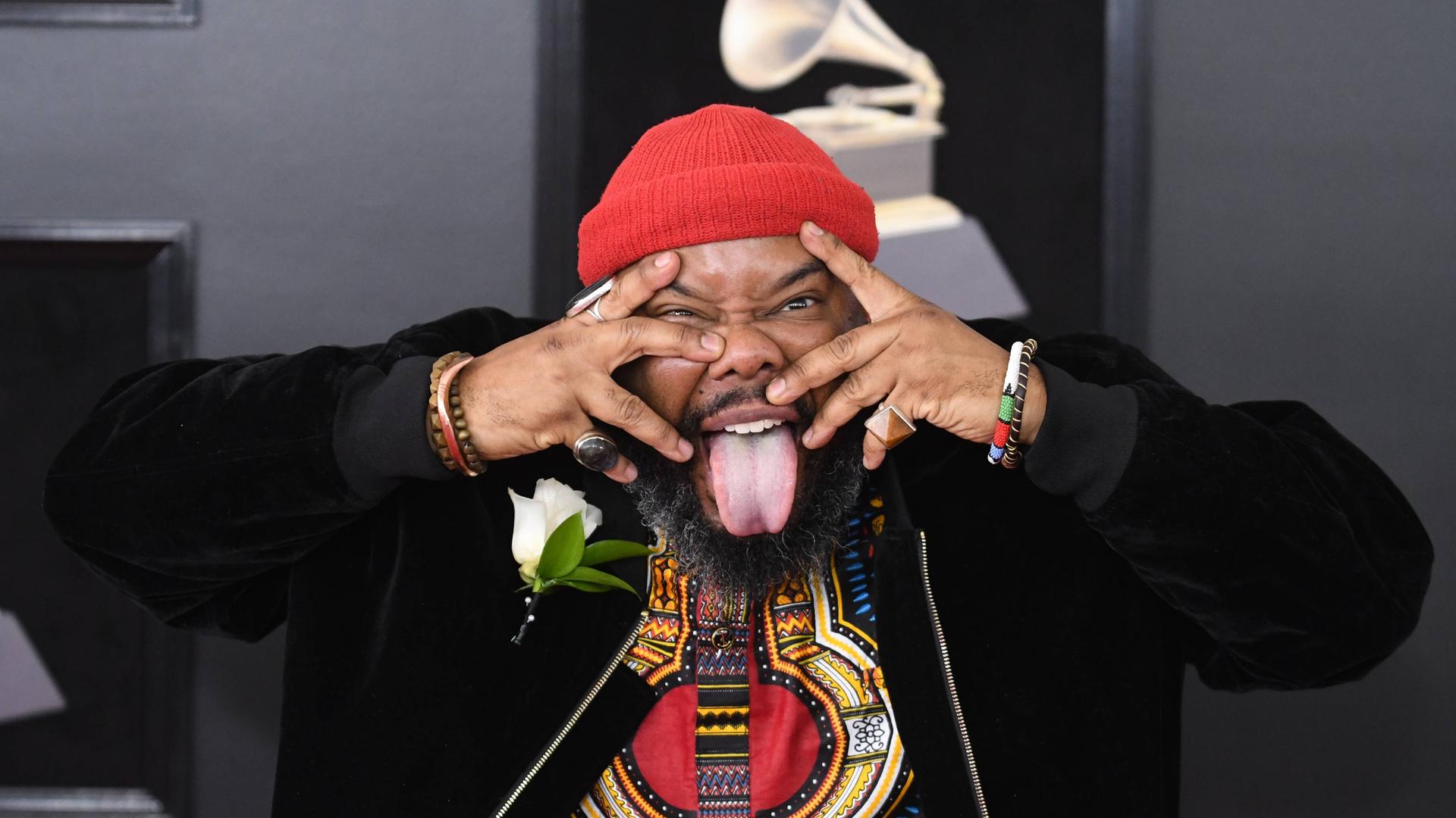 Der Musiker Kokayi hält sich auf der Grammy-Verleihung die Finger vors Gesicht und streckt die Zunge raus. Der Musiker Kokayi hält sich auf der Grammy-Verleihung die Finger vors Gesicht und streckt die Zunge raus.