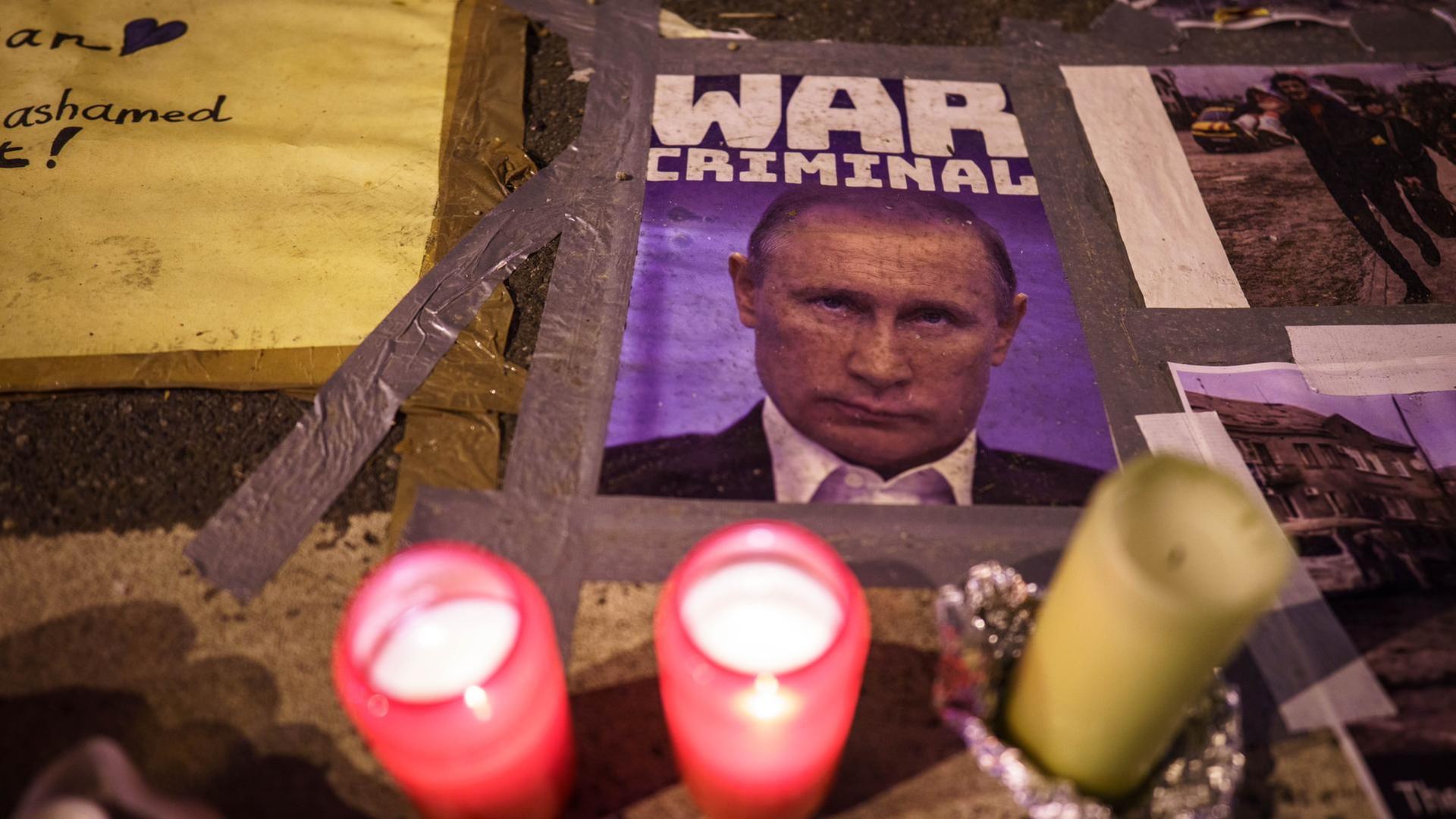 Ukraine-Krieg - Russisches Konsulat in Frankfurt/Main. Kerzen brennen vor einem Bild des russischen Präsidenten Putin, das ihn als «War Criminal» (Kriegsverbrecher) bezeichnet, auf dem Pflaster vor dem russischen Konsulat. Ukraine-Krieg - Russisches Konsulat in Frankfurt/Main. Kerzen brennen vor einem Bild des russischen Präsidenten Putin, das ihn als «War Criminal» (Kriegsverbrecher) bezeichnet, auf dem Pflaster vor dem russischen Konsulat.