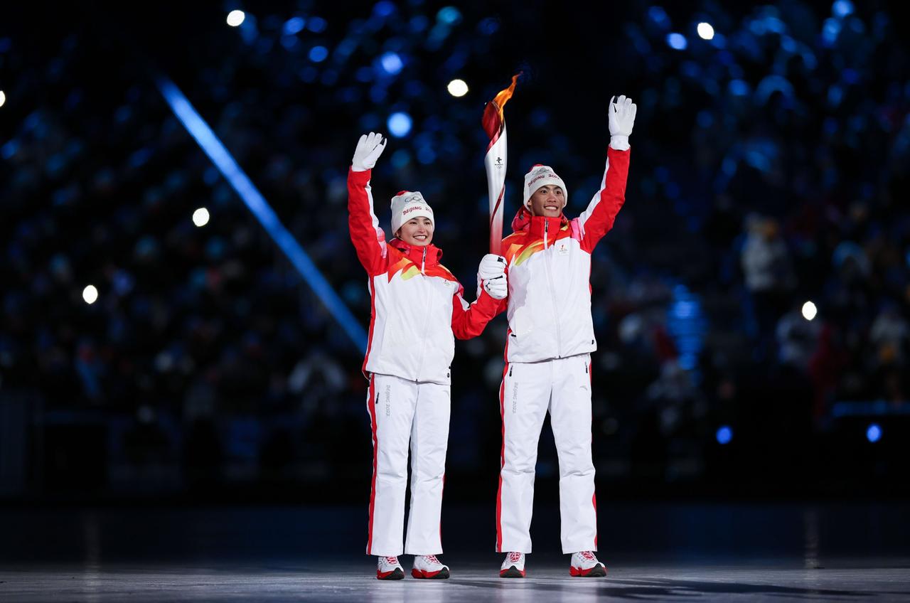 Die beiden Fackelläufer, die uigurische Langläuferin im chinesischen Team, Dinigeer Yilamujiang (l), und der Nordische Kombinierer Zhao Jiawen, stehen mit der Olympischen Fackel bei der Eröffnungsfeier der Olympischen Spiele.