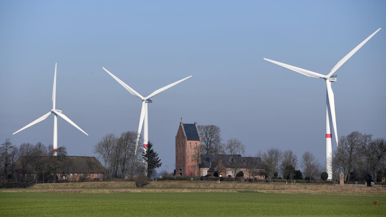 Blick auf das Dorf Klixbüll in Nordfriesland in Schleswig-Holstein: Die St.-Nikolaus-Kirche ist umgeben von drei Windrädern. Blick auf das Dorf Klixbüll in Nordfriesland in Schleswig-Holstein: Die St.-Nikolaus-Kirche ist umgeben von drei Windrädern.