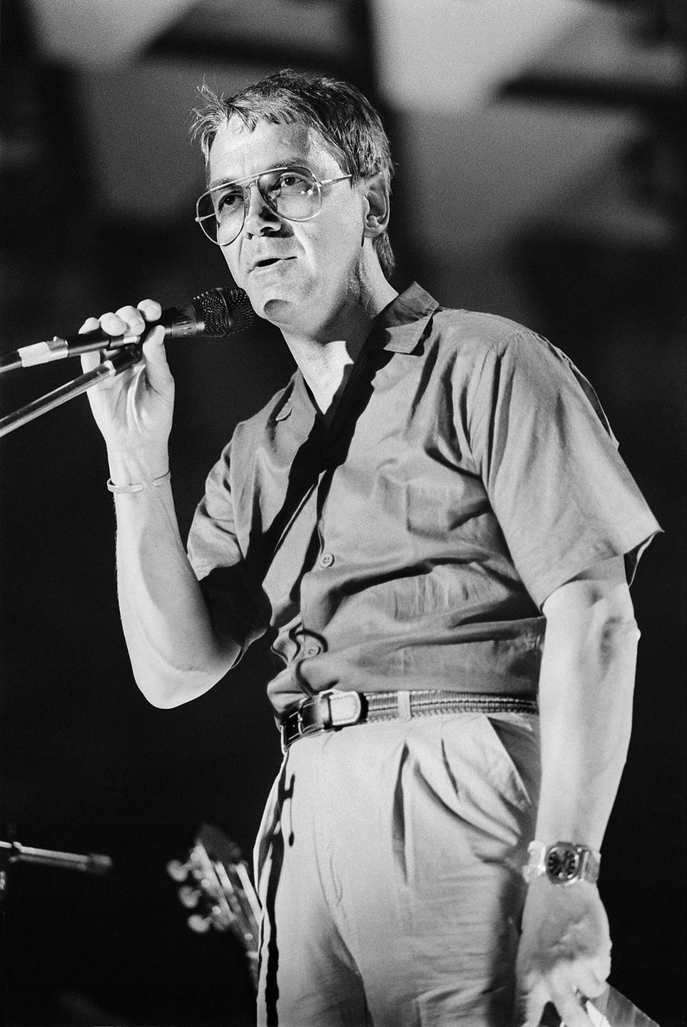 Claude Nobs 1985. Ein Mann steht auf einer Bühne und spricht in ein Mikrofon. Claude Nobs 1985. Ein Mann steht auf einer Bühne und spricht in ein Mikrofon.