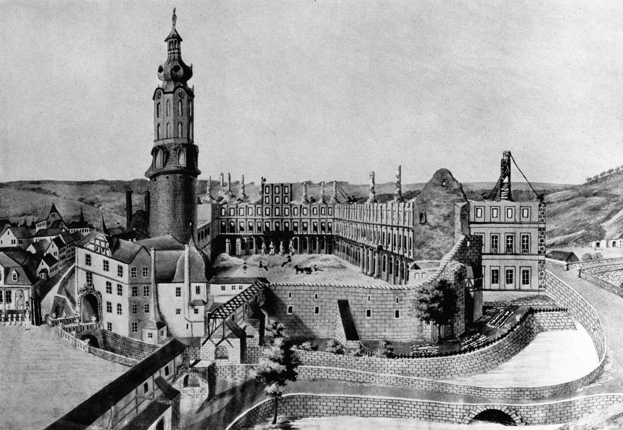 Ein schwarz-weiß-Bild zeigt die Ruinen des Stadtschlosses, bei dem nur einige Fassadenwände und Kaminschornsteine übrig geblieben sind. 