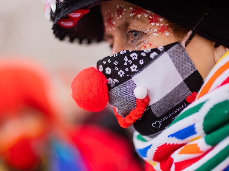 Eine Karnevalistin in Köln feiert mit medizinischer Maske und Kostüm beim Auftakt der Karnevalssession auf dem Heumarkt