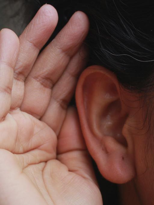 Wie können wir uns beim Hören selbst zuhören? Zu sehen: Eine Hand ist geöffnet an einem Ohr. 