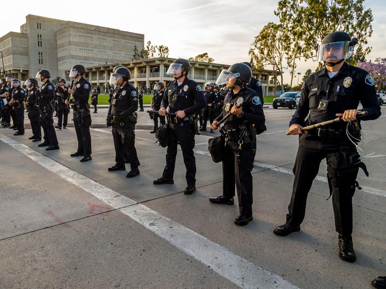 Bewaffnete Polizisten stehen in einer Reihe, um bei einer Demonstration eine Straße zu blockieren.