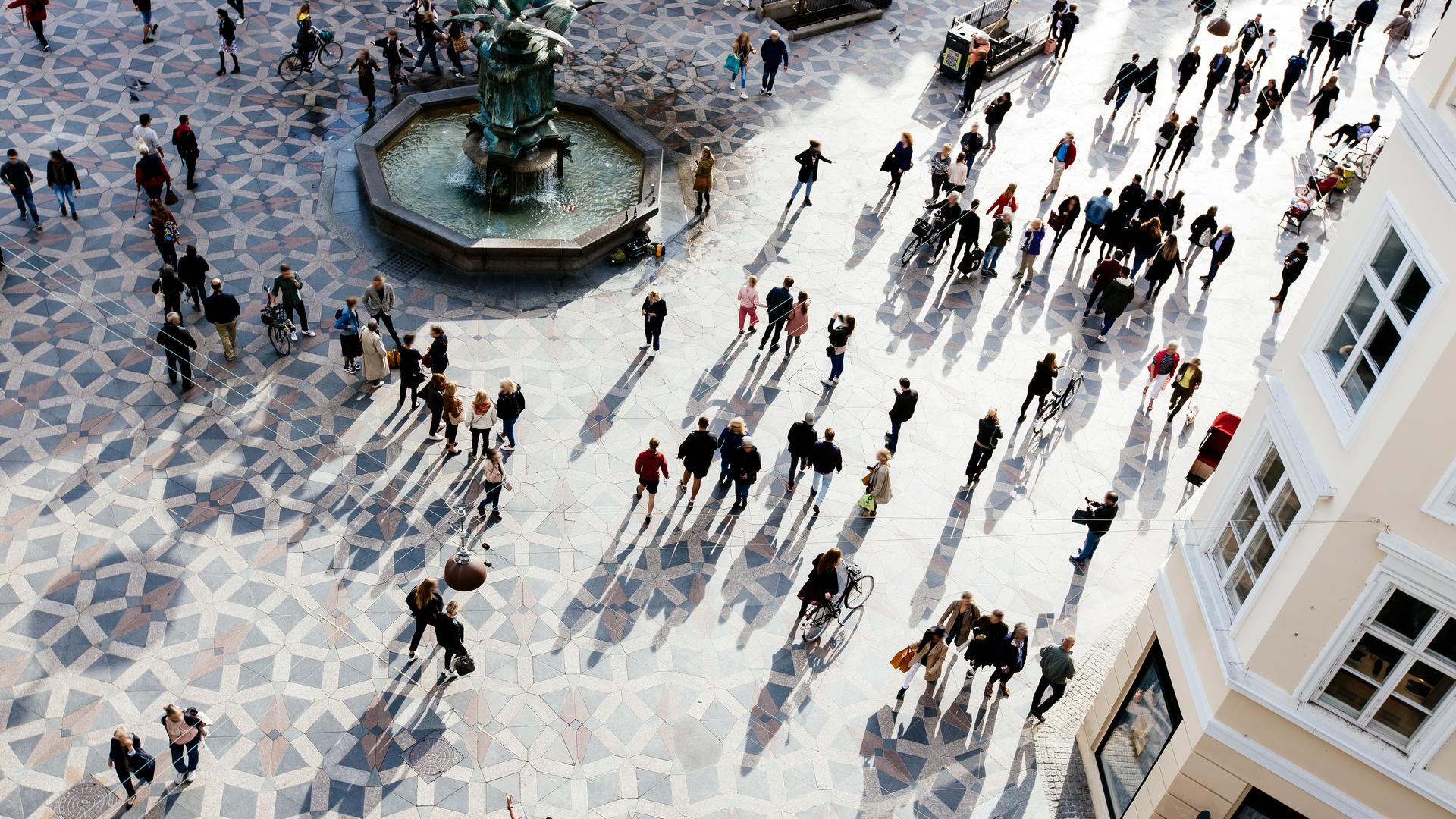 Blick von oben auf den Hauptplatz von Amagertorv im Abendlicht. Die langen Schatten der Fußgänger*innen bilden sich auf dem gemusterten Boden ab. Blick von oben auf den Hauptplatz von Amagertorv im Abendlicht. Die langen Schatten der Fußgänger*innen bilden sich auf dem gemusterten Boden ab.