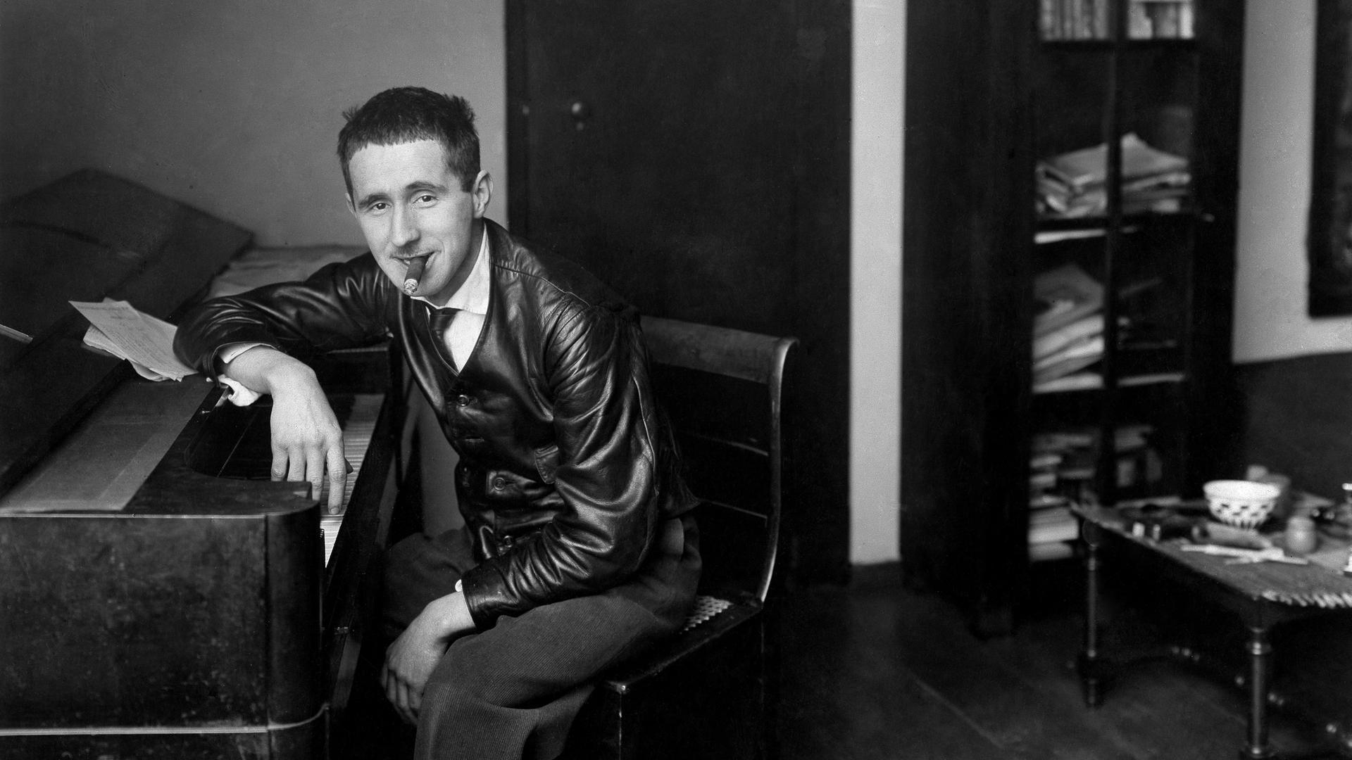 Historische Aufnahme um 1927. Bertolt Brecht sitzt mit Zigarre im Mund an einem Klavier und schaut selbstbewußt Richtung Betrachter. Historische Aufnahme um 1927. Bertolt Brecht sitzt mit Zigarre im Mund an einem Klavier und schaut selbstbewußt Richtung Betrachter.