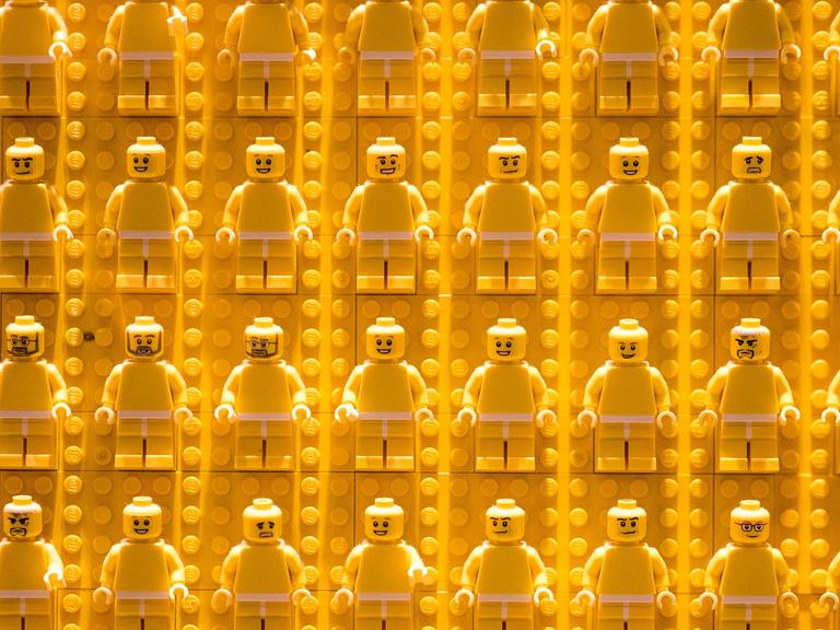 Reihen von gelben Legofiguren vor gelbem Legohintergrund.