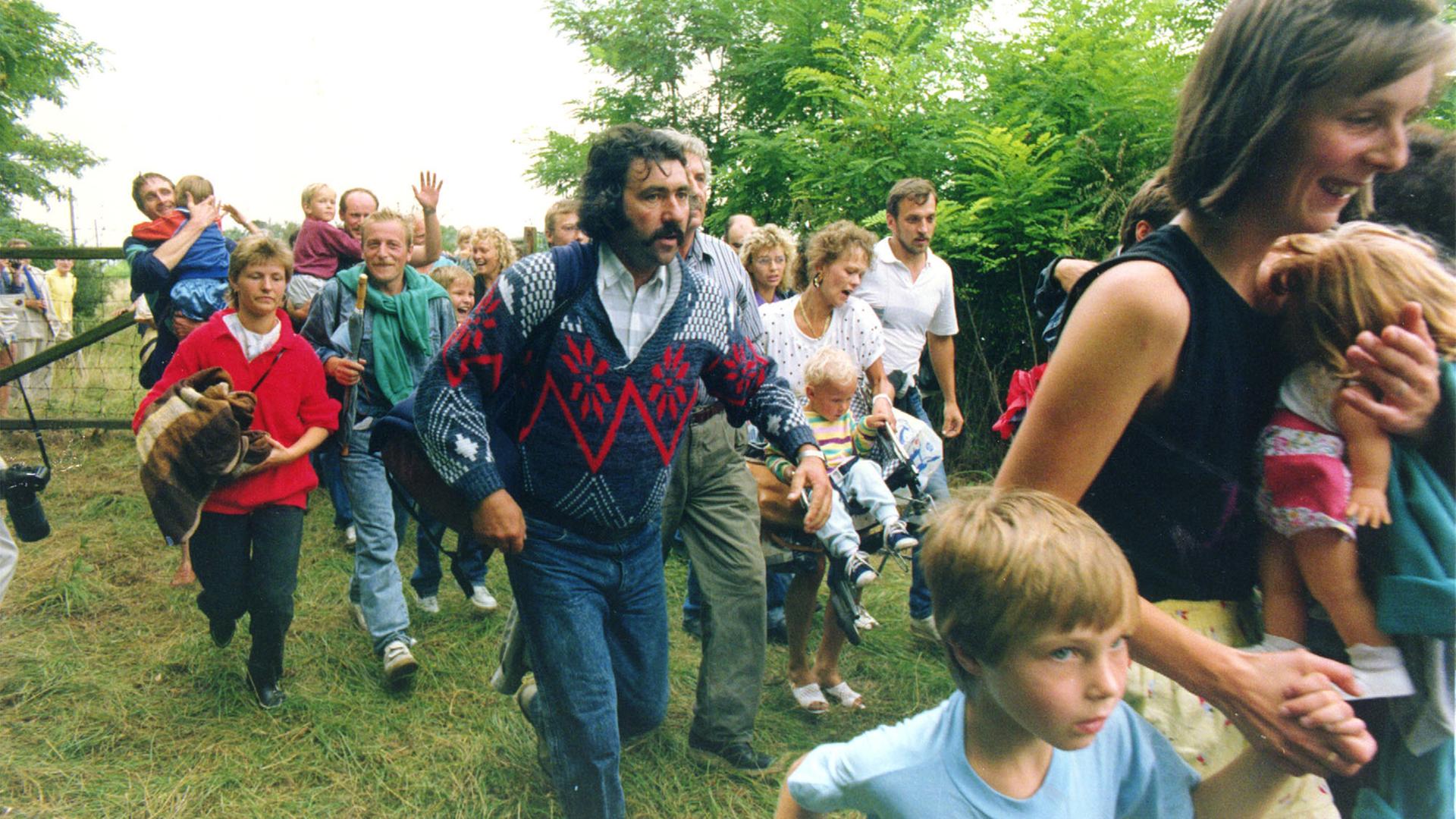 Mehrere Hundert DDR-Bürger rennen am 19. August 1989 im Laufschritt durch ein Holztor über die ungarisch-österreichische Grenze nach Mörbisch auf der oesterreichischen Seite. Mehrere Hundert DDR-Bürger rennen am 19. August 1989 im Laufschritt durch ein Holztor über die ungarisch-österreichische Grenze nach Mörbisch auf der oesterreichischen Seite.