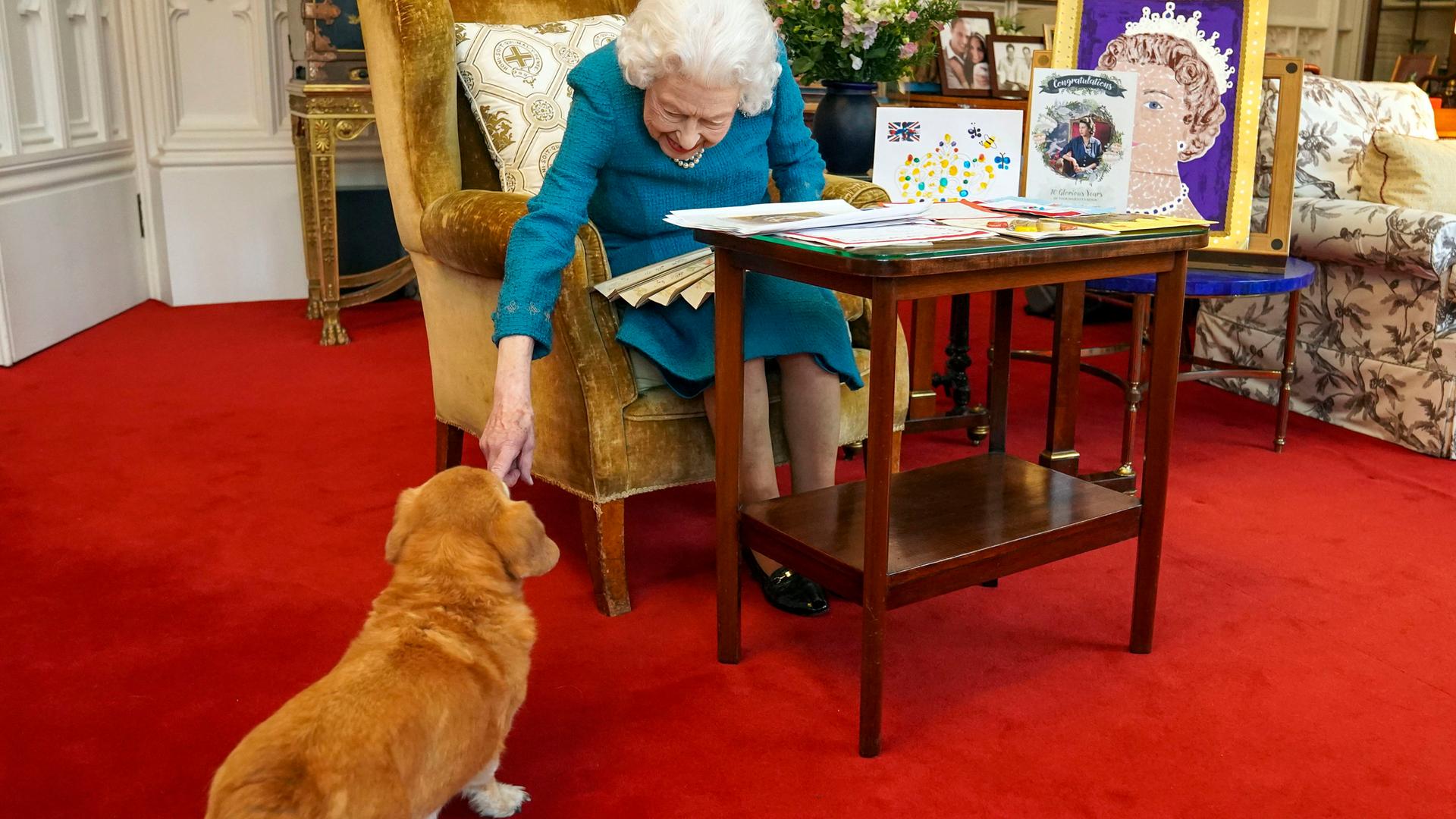 Queen Elizabeth II. sitzt in einem Sessel und streichelt einen ihrer Hunde. Queen Elizabeth II. sitzt in einem Sessel und streichelt einen ihrer Hunde.