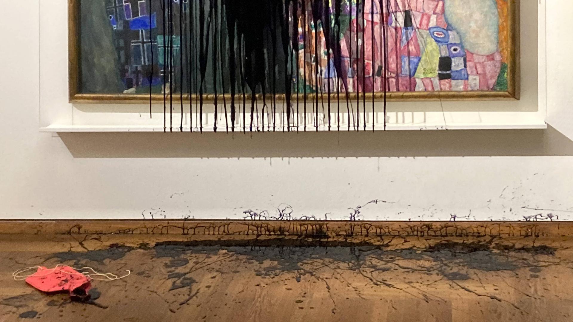Detail des Gemäldes "Leben und Tod" von Gustav Klimt, was mit schwarzem Öl übergossen ist. Die Wand an der das Gemälde hängt und der Boden des Museums sind ebenfalls mit Öl bedeckt. Detail des Gemäldes "Leben und Tod" von Gustav Klimt, was mit schwarzem Öl übergossen ist. Die Wand an der das Gemälde hängt und der Boden des Museums sind ebenfalls mit Öl bedeckt.