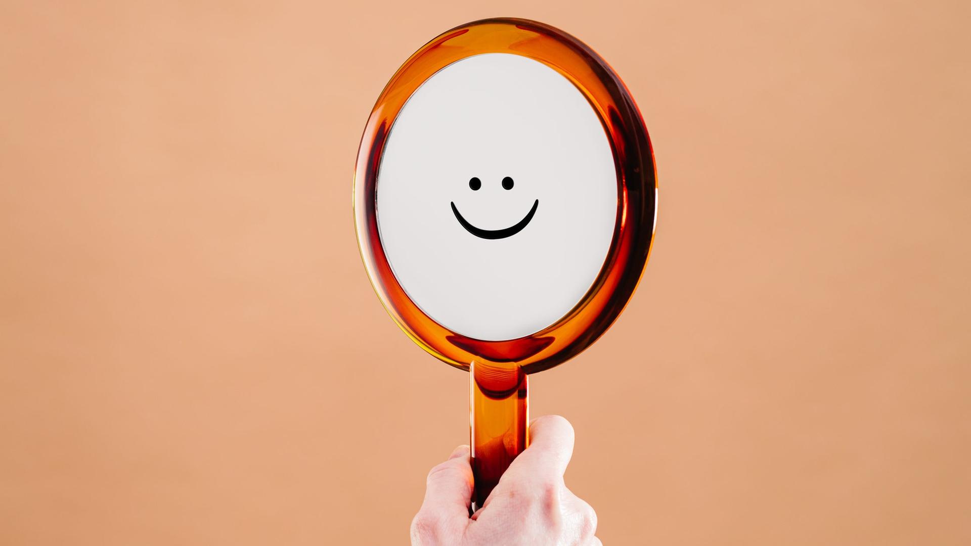 Ein aufgemalter Smiley auf einem Handspiegel