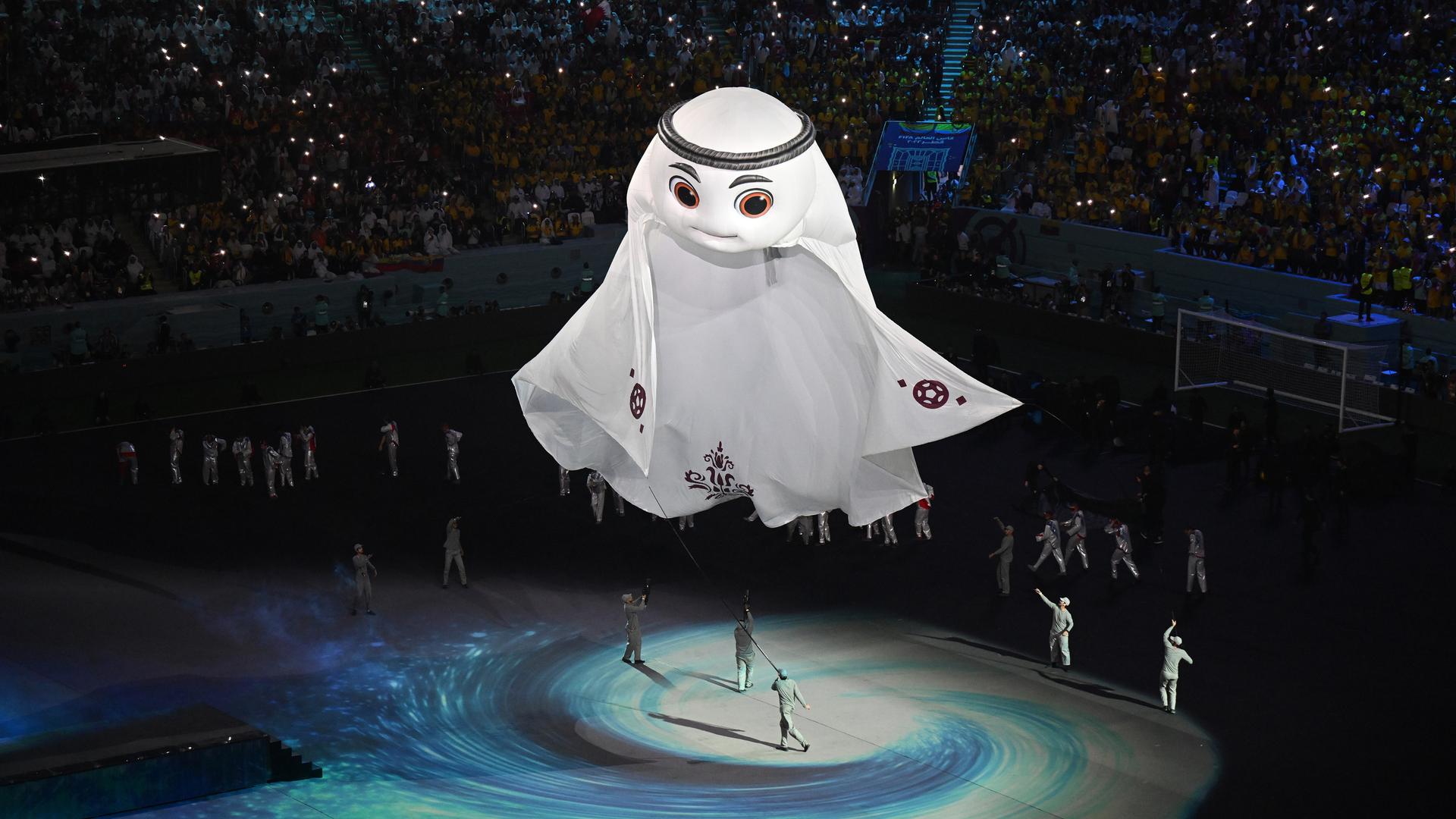 Künstler tanzen während der Eröffnungsfeier der Fußball-WM. In der Mitte schwebt ein riesiges weißes Maskottchen ins Stadion. Künstler tanzen während der Eröffnungsfeier der Fußball-WM. In der Mitte schwebt ein riesiges weißes Maskottchen ins Stadion.