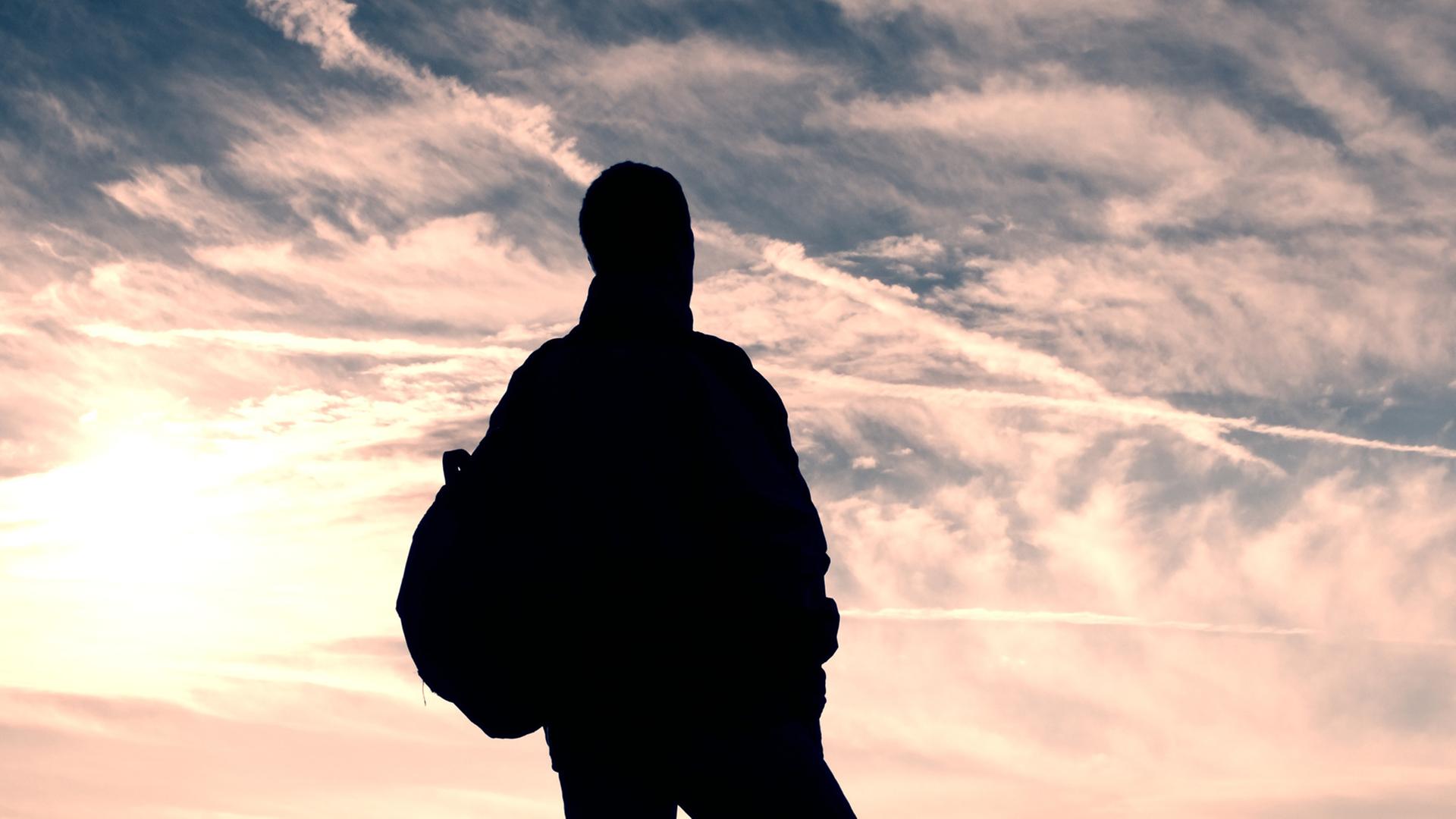Ein namenloser Mann im Nirgendwo unterwegs. Zu sehen: Ein Mann steht mit dem Rücken zur Kamera und schaut in die Wolken. Ein namenloser Mann im Nirgendwo unterwegs. Zu sehen: Ein Mann steht mit dem Rücken zur Kamera und schaut in die Wolken.