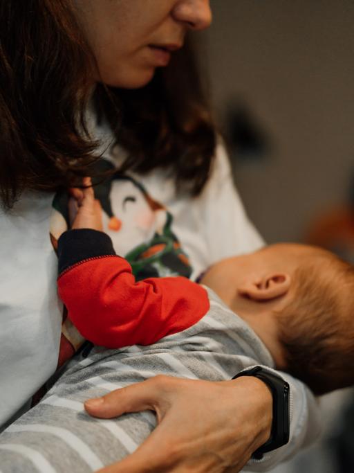 Eine Frau mit einem Baby auf dem Arm, das an ihrer Brust trinkt.