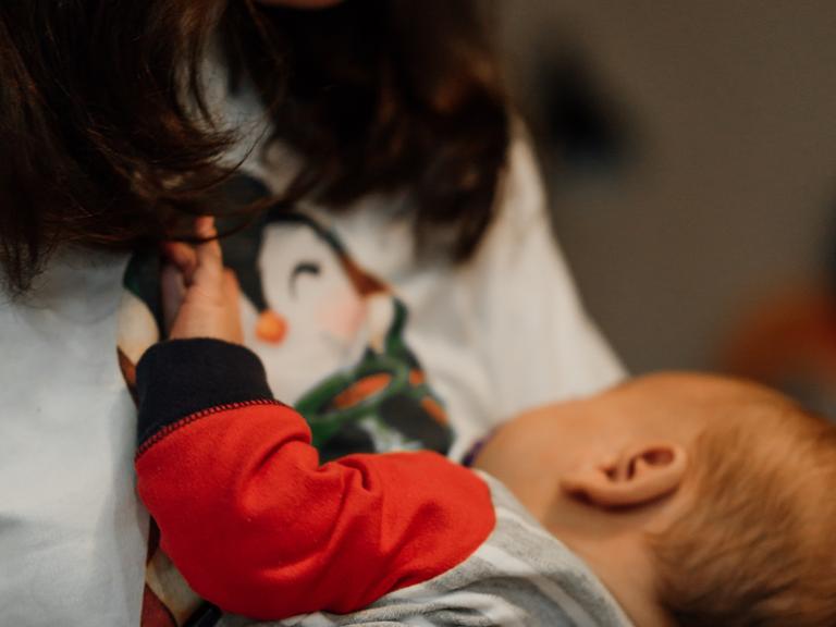 Eine Frau mit einem Baby auf dem Arm, das an ihrer Brust trinkt.