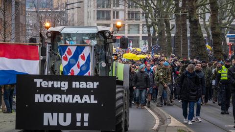 Ein Traktor und Demonstranten in der niederlänischen Hauptstadt Amsterdam. Auf einem Schild ist zu lesen: "Zurück zur Normalität jetzt".