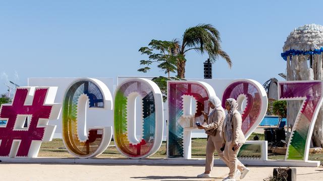 Zwei Teilnehmer der UN-Klimakonferenz gehen am COP27-Logo vorbei