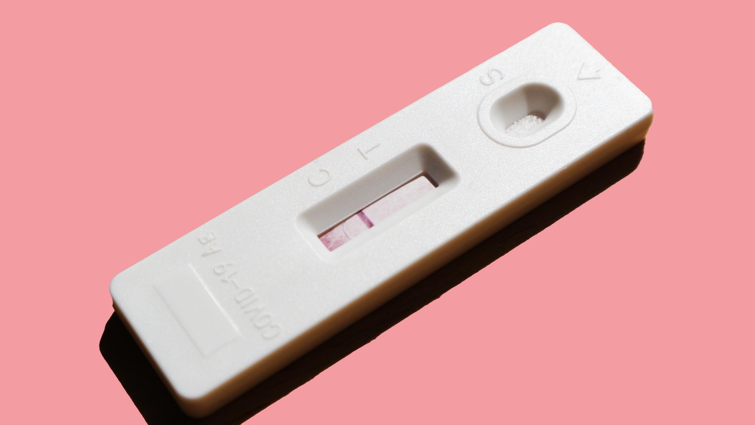 Ein Covid-19-Selbsttest auf rosafarbenem Untergrund mit einer roten Linie im Bereich C. Ein Covid-19-Selbsttest auf rosafarbenem Untergrund mit einer roten Linie im Bereich C.