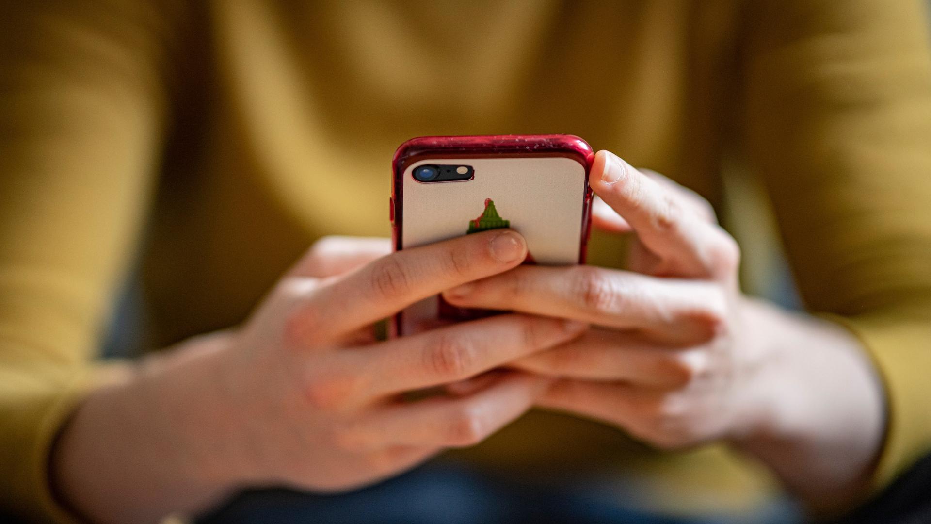 Eine junge Frau hält ein Smartphone in der Hand. Eine junge Frau hält ein Smartphone in der Hand.