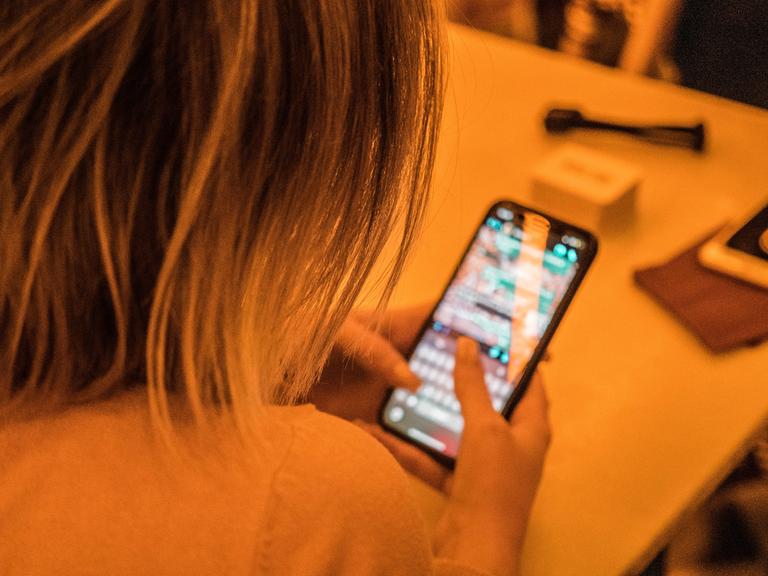 Eine Person tippt an ihrem Smartphone eine Nachricht.